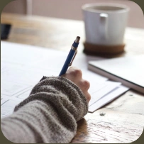 A writer taking notes beside a cup of coffee