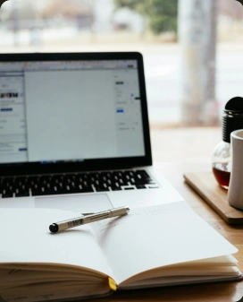 An open notebook and pen in front of a laptop