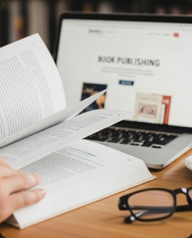 A manuscript beside a laptop displaying book publishing