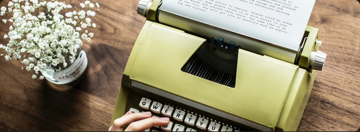 A vintage green typewriter and white flowers on a wooden desk